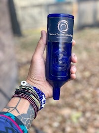 a person holding a blue bottle with a tattoo on it