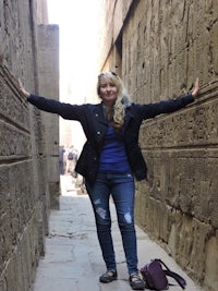 a woman standing in an alleyway with her arms outstretched
