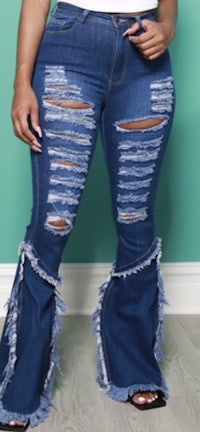 a woman wearing flared jeans with ripped hems
