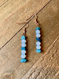 a pair of blue and white earrings on a wooden surface