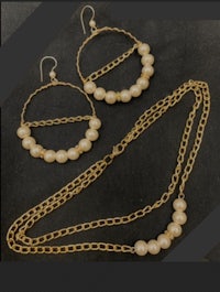 a gold chain necklace with pearls and hoop earrings