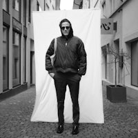 a black and white photo of a man standing in front of a wall