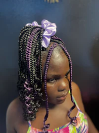 a young girl with braided hair in a purple bow