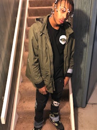 a young man in a green jacket standing on stairs