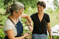 two women in overalls working together in a garden