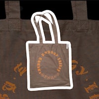 a brown tote bag with an orange logo on it