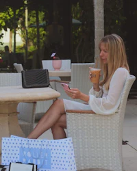 a woman sitting at a table with a cup of coffee and shopping bags