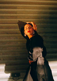 a woman in a black coat leaning against a wall