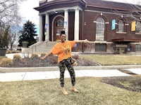 a woman standing in front of a building with her arms outstretched