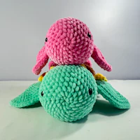a pink and green stuffed animal sitting on top of each other
