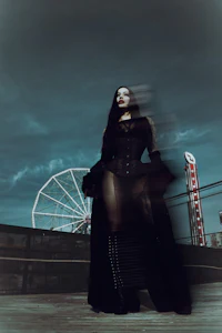 a woman in a black dress standing in front of a ferris wheel