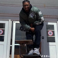 a man sitting on a stool in front of a building