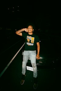a man sitting on the side of a car at night