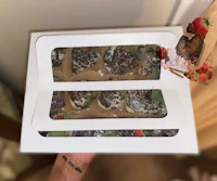 a person is holding a box of chocolate covered strawberries