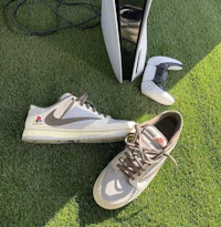 a pair of sneakers on the grass next to a ps4 controller