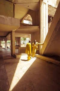 a man in a yellow suit is walking down a hallway