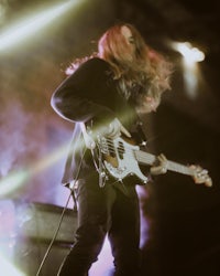 a man with long hair playing a bass at a concert