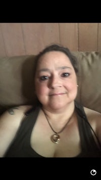 a woman sitting on a couch with a tattoo on her chest