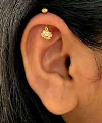 a woman's ear with a gold ear piercing
