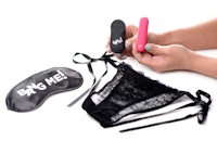 a woman is putting on a lingerie set with a pink and black sex toy