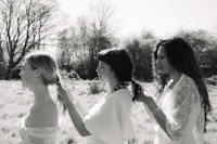 a black and white photo of three brides in a field