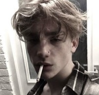 a young man with long hair smoking a cigarette
