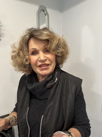 a woman in a black vest holding a glass of wine
