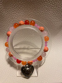 a clear glass holder with orange and pink beads on it
