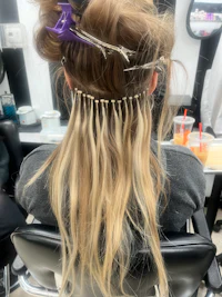 a woman with long blonde hair sitting in a chair at a salon