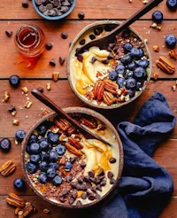 two bowls of oatmeal with blueberries and pecans