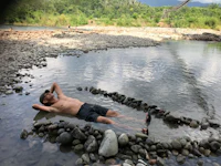 a man laying on rocks in a river