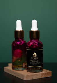 two bottles of rose oil on a wooden board
