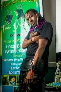 a man with dreadlocks standing in front of a sign
