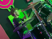 a young man playing drums in front of a green screen