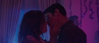 a man and woman kissing in front of a purple light