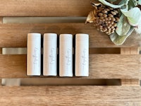four lip balms sitting on a wooden tray