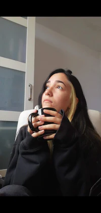 a woman sitting in a chair holding a cup of coffee