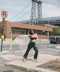 a woman standing on a street in front of the brooklyn bridge