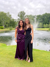 two girls standing in front of a fountain in a park