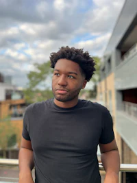 a black man with afro hair standing on a balcony