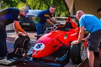 a group of men working on a red racing car