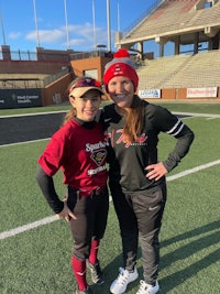 two softball players posing for a picture on a field