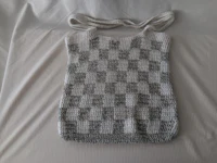 a white and grey crocheted bag on a bed