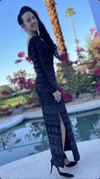 a woman in a black dress posing in front of a pool