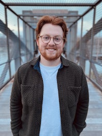 a man with glasses standing on a bridge