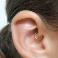 a woman's ear with a gold ear piercing