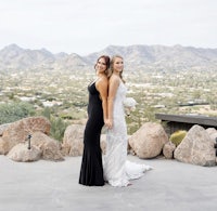 two brides posing for a photo in front of a mountain