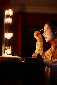 a man is putting on makeup in front of a mirror