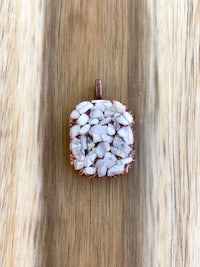 a pendant with a white stone on top of a wooden surface
