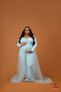 a pregnant woman in a blue dress posing for a photo